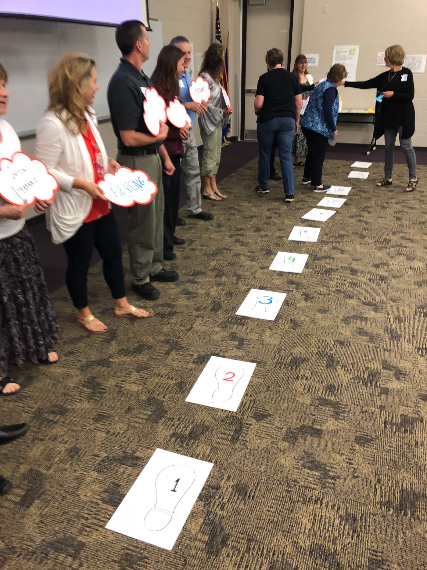 Participants standing along a path of printed cards laid across the floor