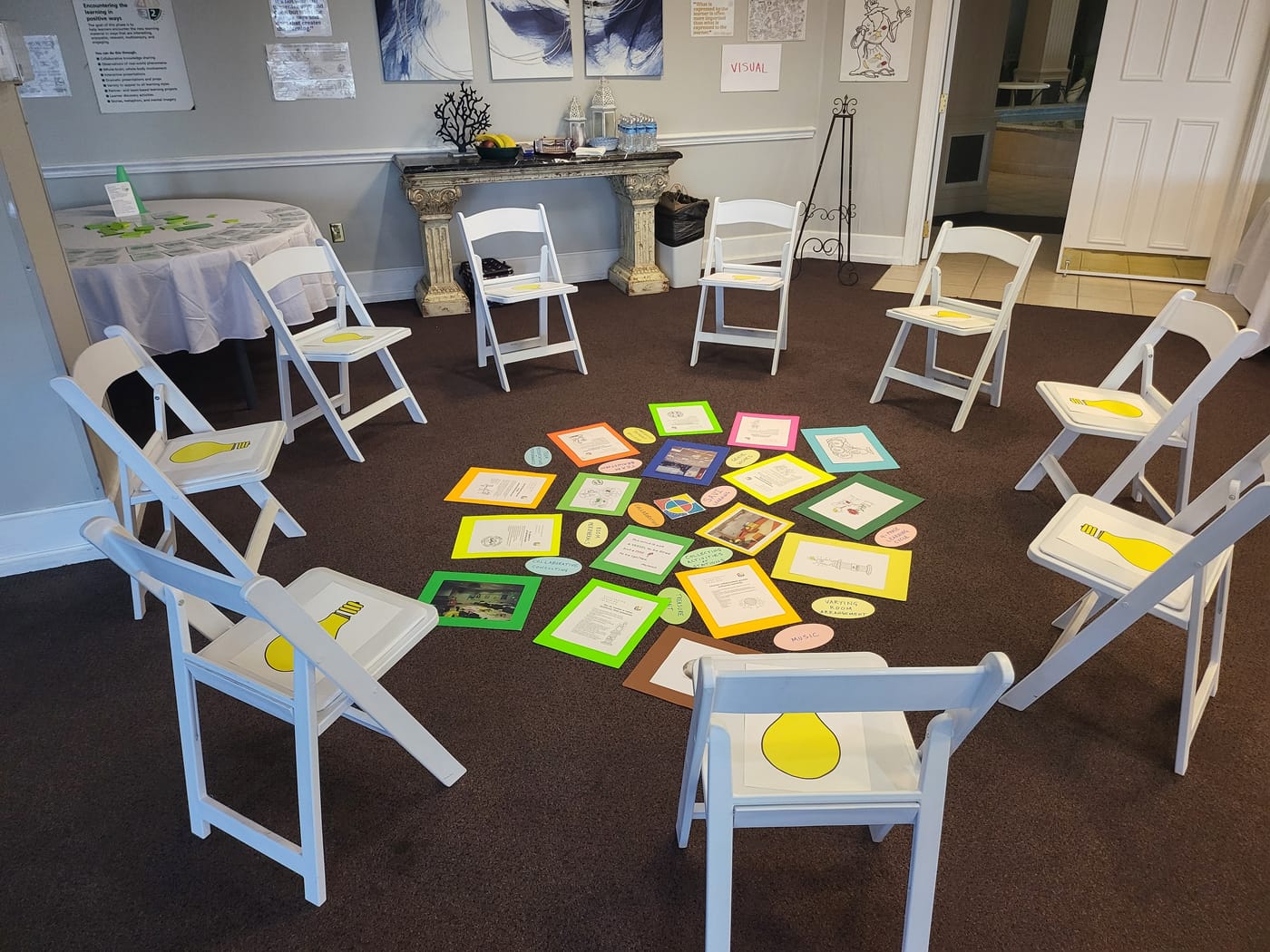 White chairs in a circle around colorful cards laid out on the floor